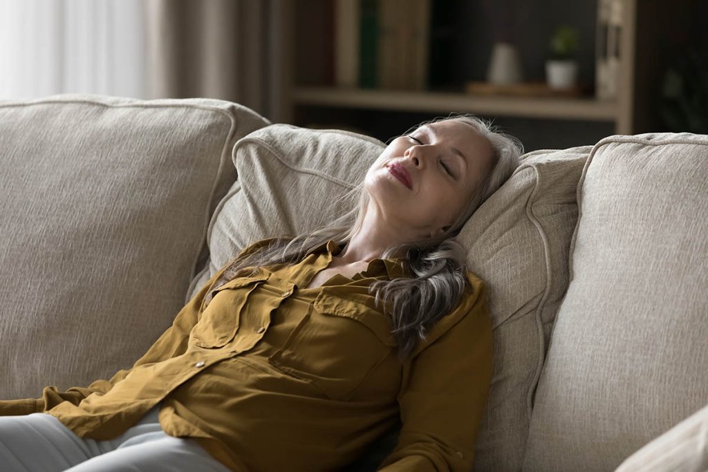middle-aged woman sleeping leaned on soft cushions looks without energy 