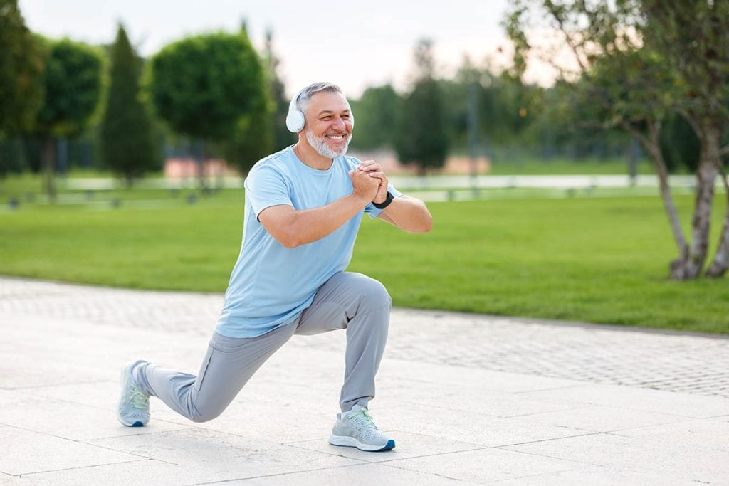 Man outdoors stretching and exercising with headphones
