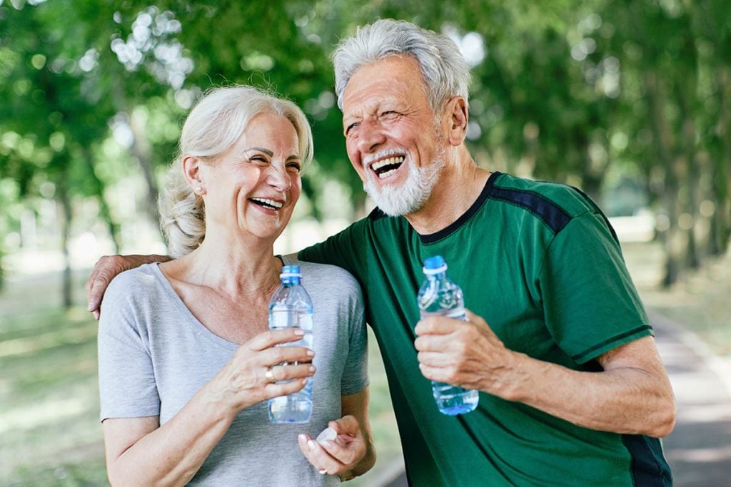 Smiling active couple holding water bottles