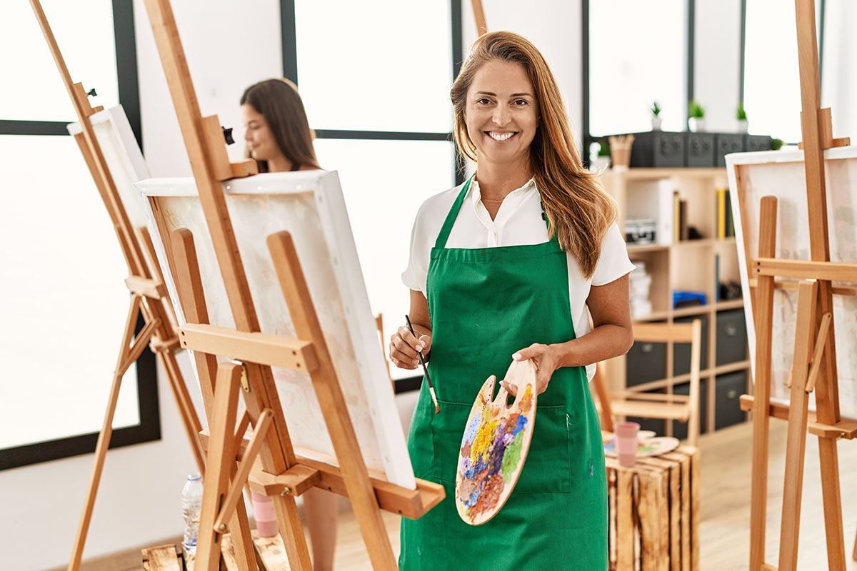 middle age woman at art classroom looking positive and happy 