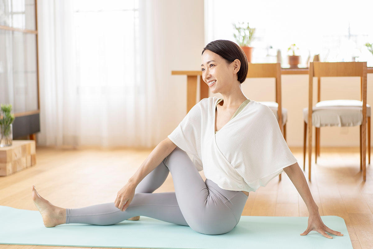 A middle-aged woman is stretching in the living room at home.