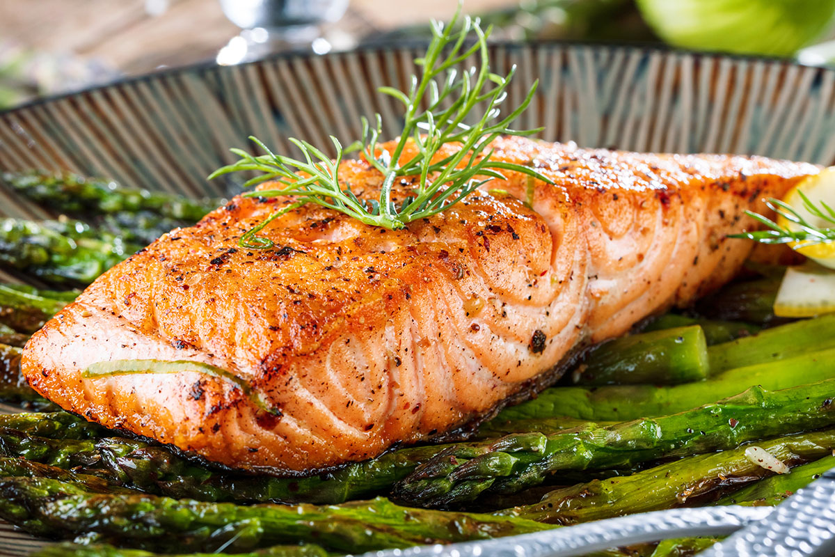 Grillen salmon filet and asparagus on wooden table close up