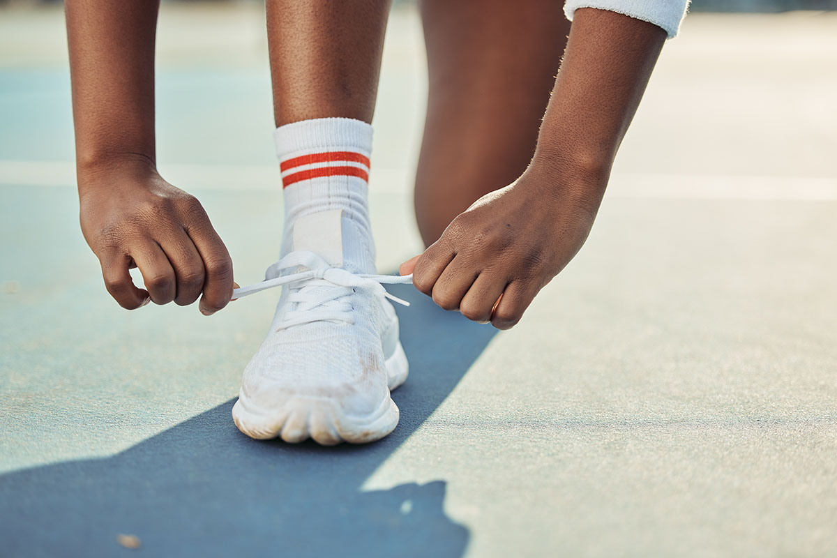 Hands, tie shoes and start tennis game, person on court with fitness and sports outdoor. 