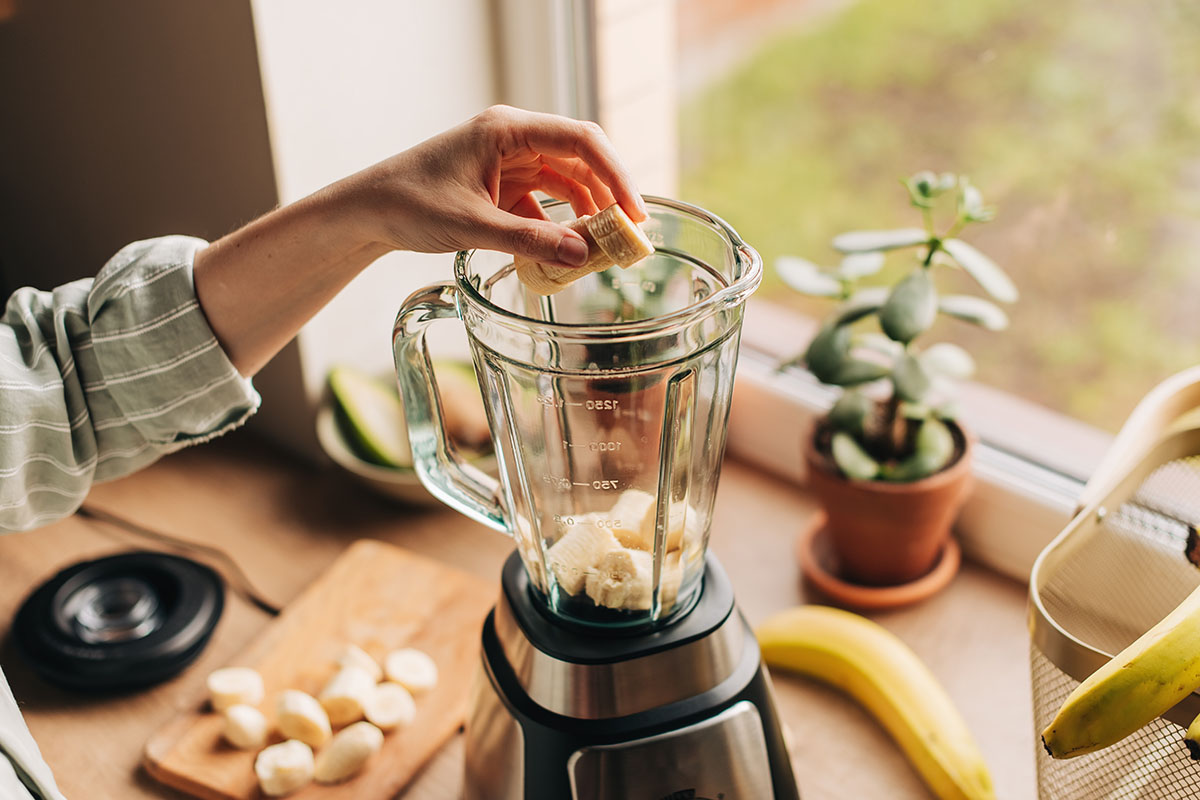 Woman is preparing a healthy detox drink in a blender - a smoothie with fresh fruits