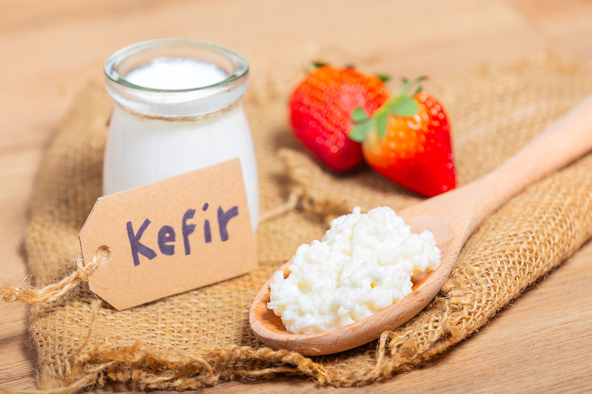 Kefir grains in wooden spoon in front of cups of Kefir Yogurt Parfaits. Kefir is one of the best health foods available providing powerful probiotics.