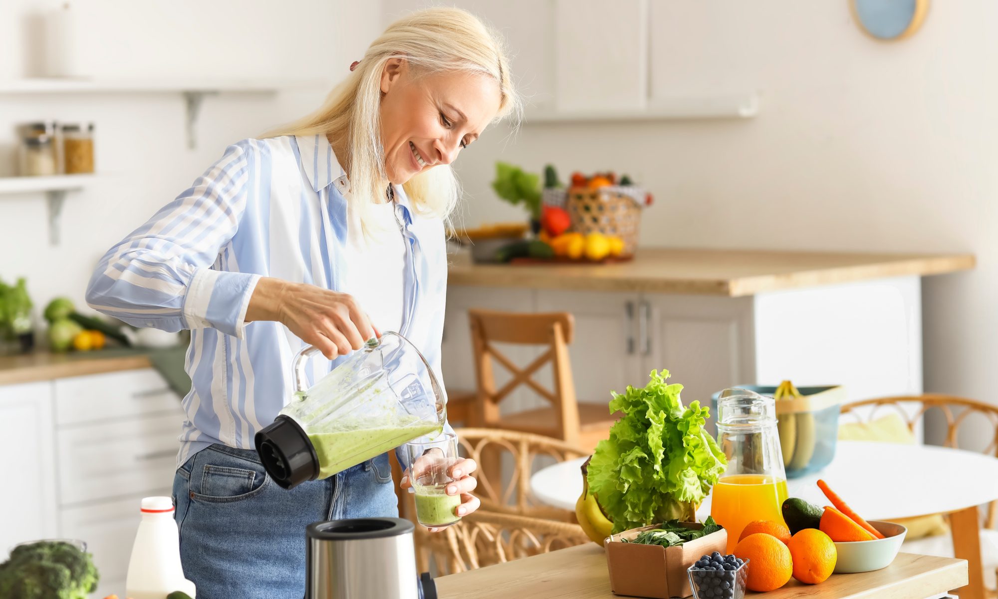 Woman making and pouring smoothie in a cup