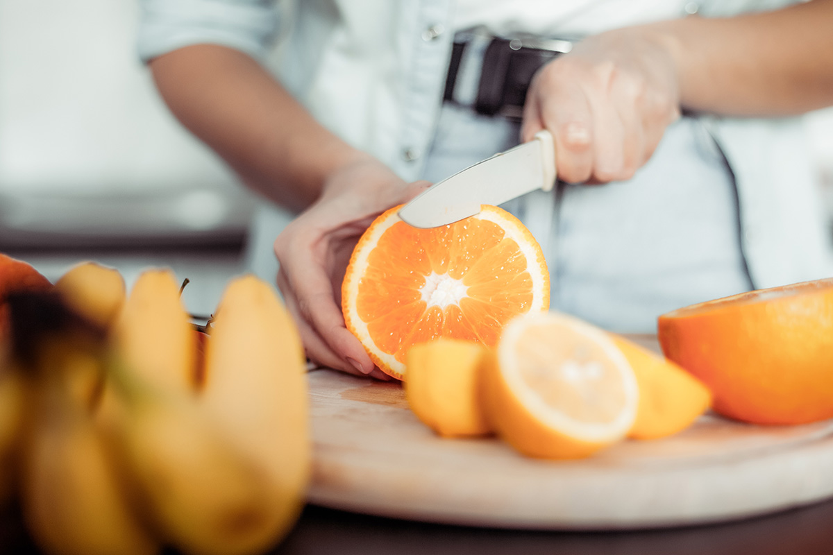 Healthy food concept. Woman cuts oranges in modern kitchen