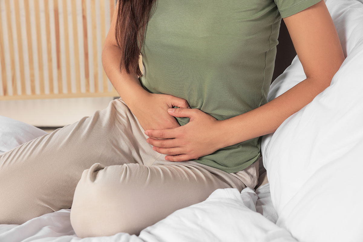 woman holding stomach in bed