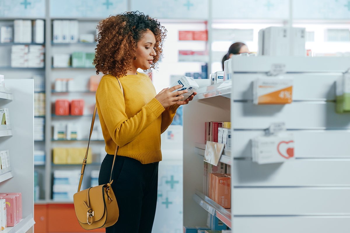 woman at the pharmacy looking at medicine bottle labels